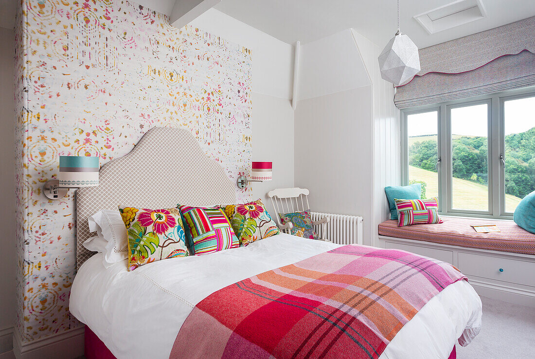 Bedroom with colourful accent wall, patterned cushions and sitting window