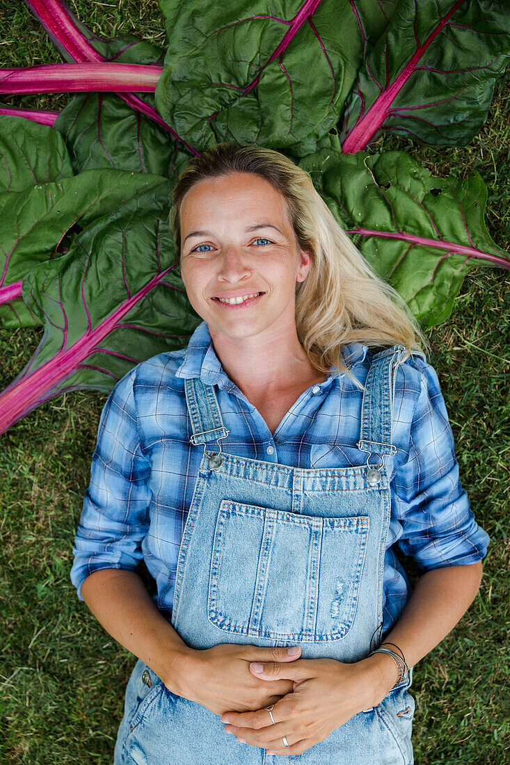 Blond woman harvesting vegetables from her raised bed in her own garden