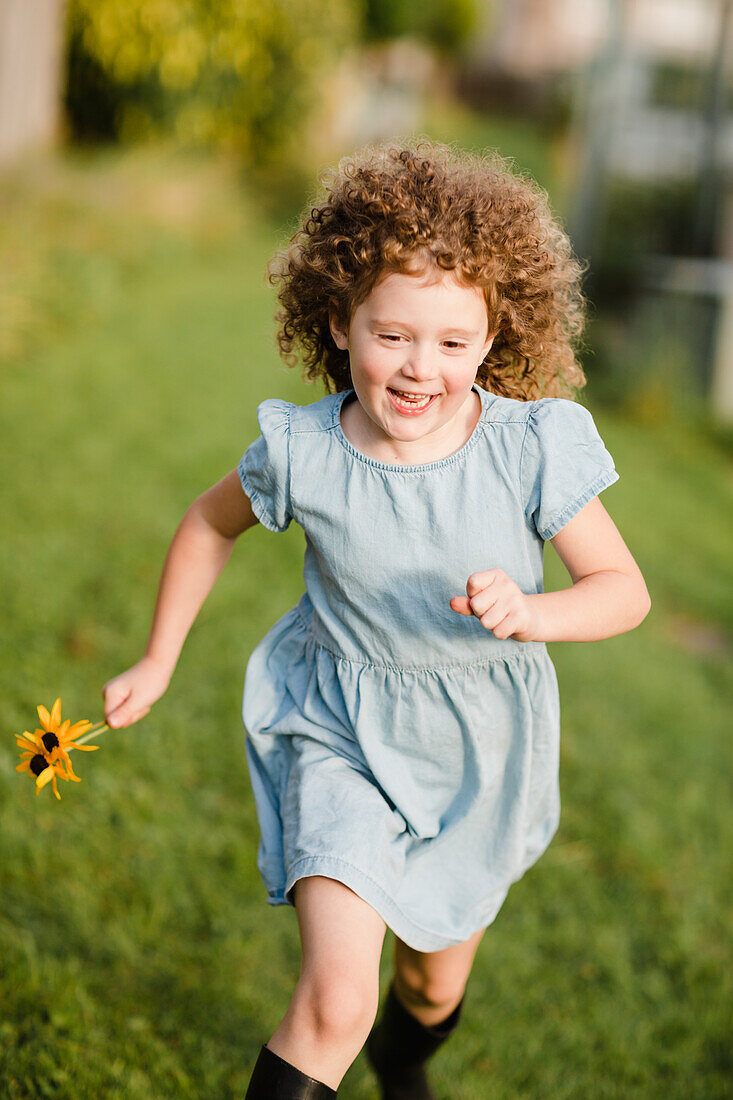 Happy little girl running on a meadow in the garden
