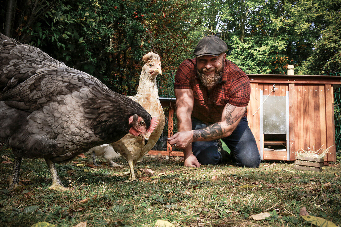 Mann in seinem eigenen Garten, Mann füttert Freilandhühner
