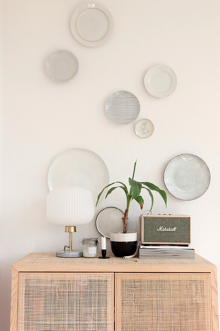 Wall decoration with plates above a rattan dresser with retro radio