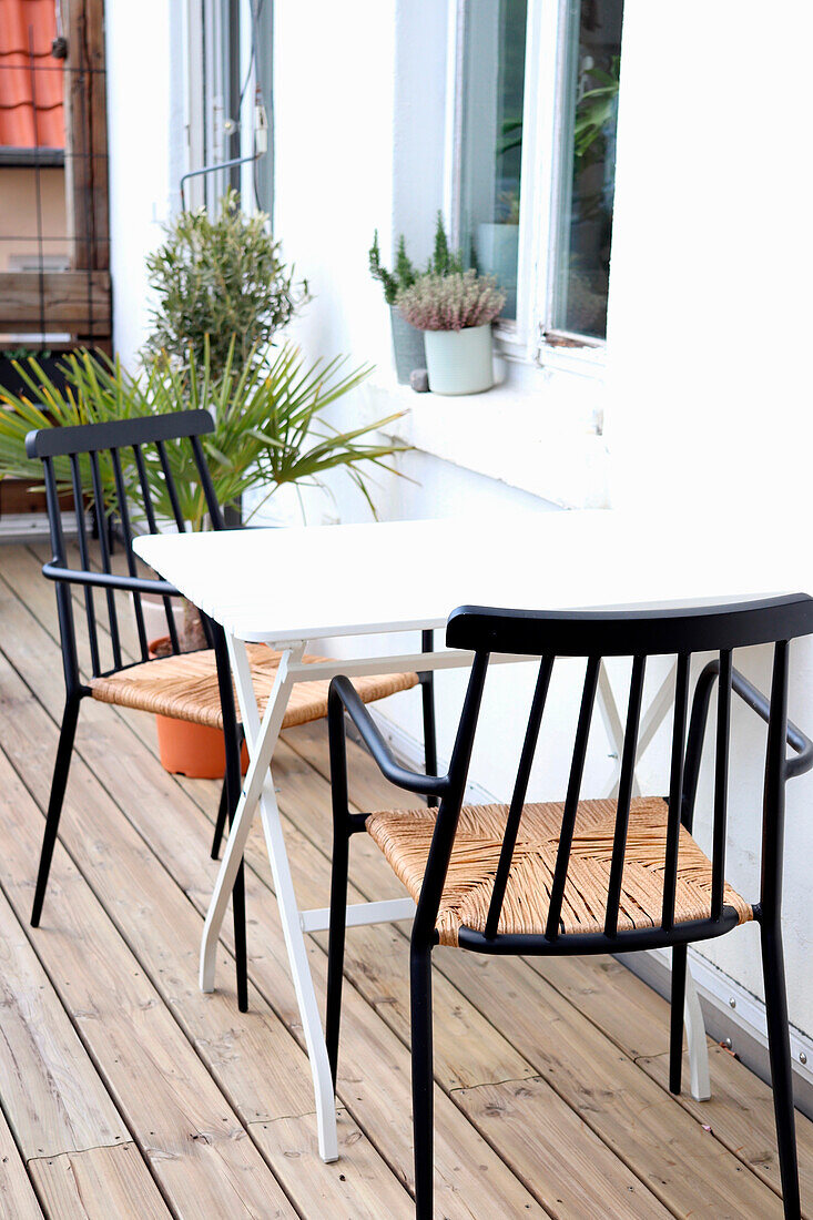 Small balcony table with black chairs and potted plants