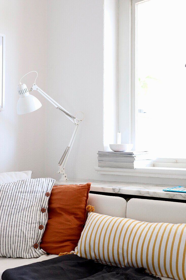 Desk lamp above sofa with striped and ochre-coloured cushions