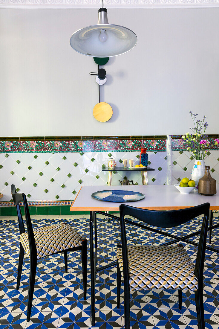 Dining table with Italian chairs in front of tiled wall with border