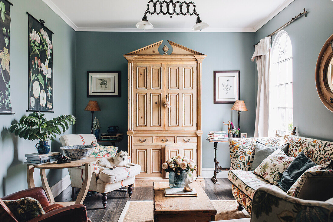 The English pine cupboard hides the TV, floral sofa in living room