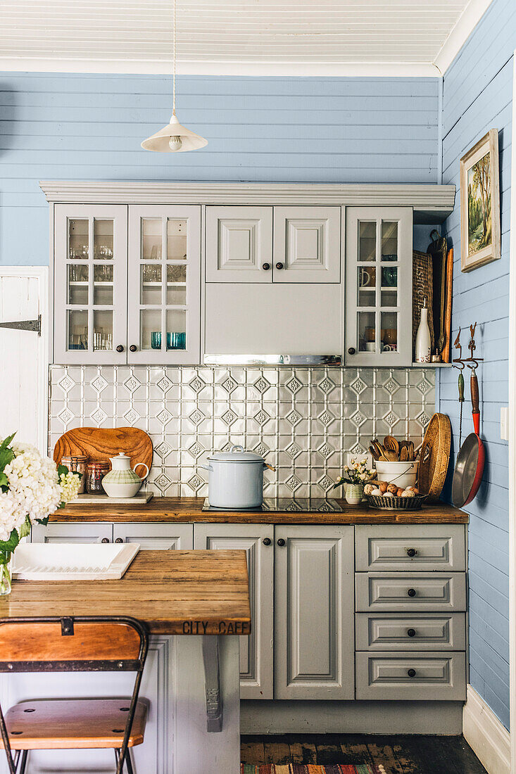 The kitchen features blue walls and a pressed tin splashback