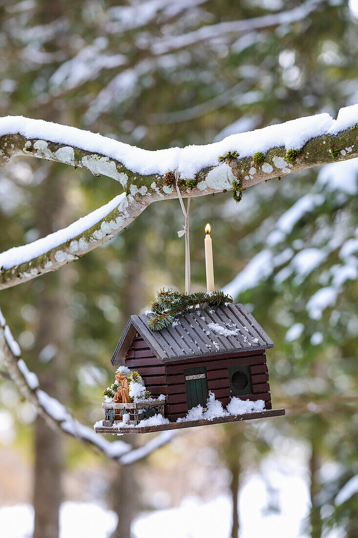 Vogelhäuschen mit Krippenfiguren im winterlichen Garten