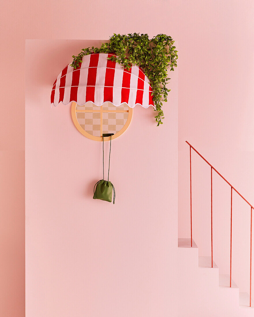 Rot-weiß gestreifte Markise am runden Fenster an rosa Wand