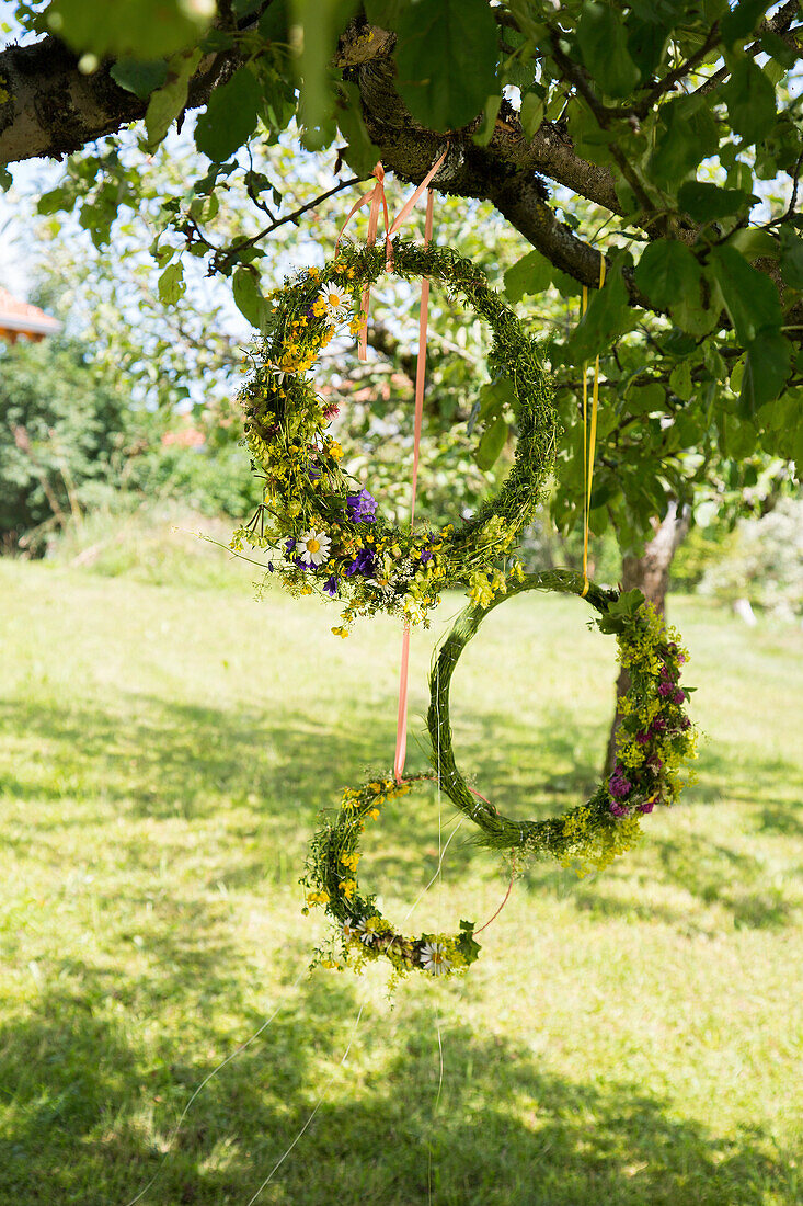 Flower wreaths on tree in summer garden