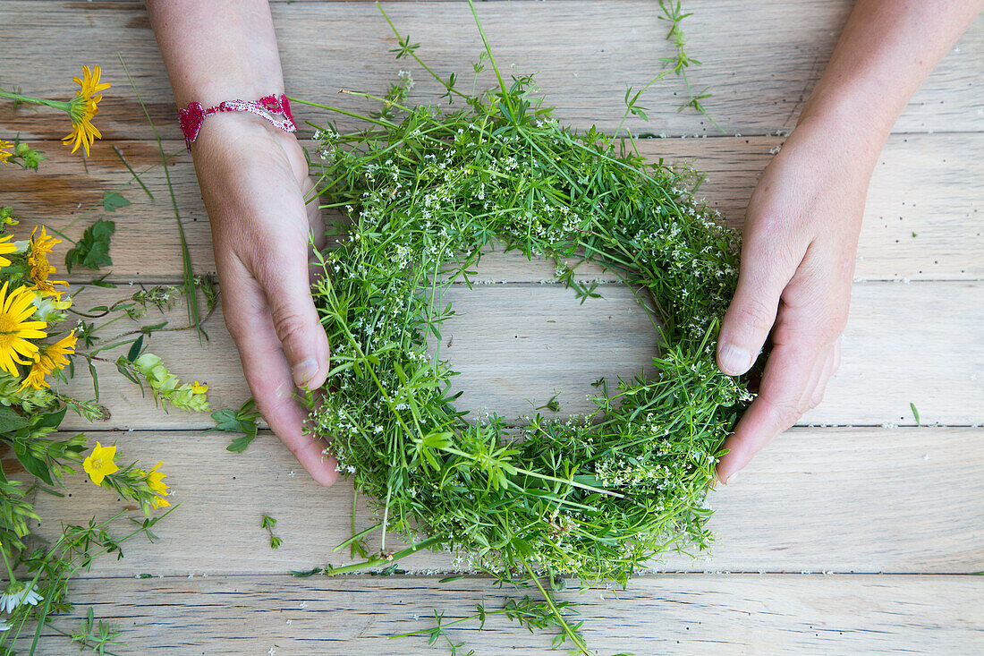 Homemade wreath made from fresh meadow flowers and grasses on a wooden table