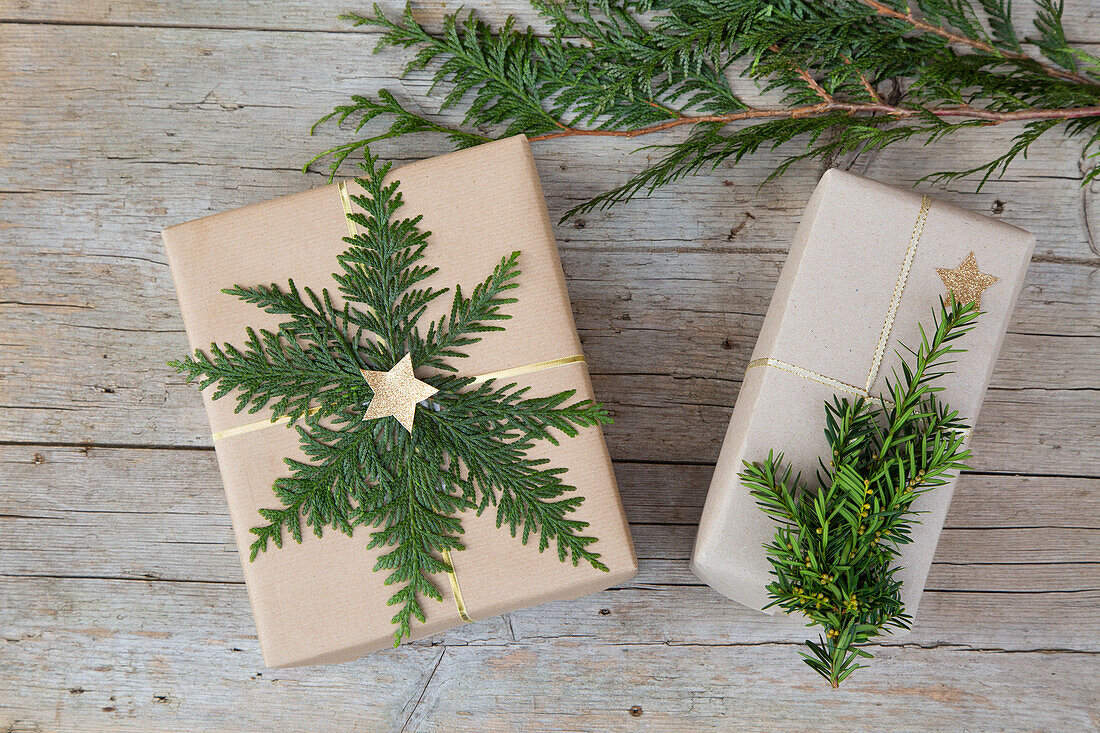 Christmas presents decorated with fir branches and stars on a wooden background