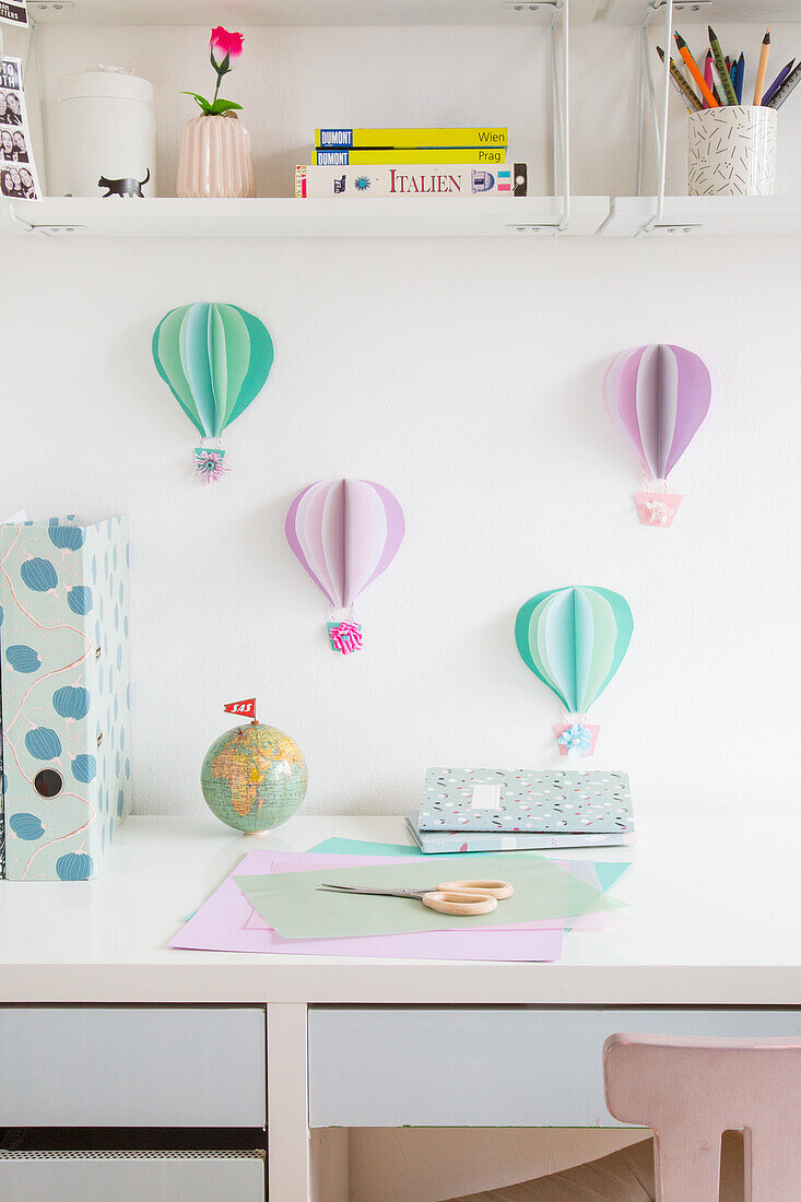 Schreibtisch mit DIY-Heißluftballons aus Papier an der Wand