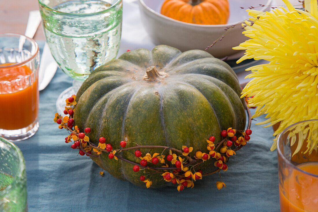 Pumpkin with berry wreath as table decoration, glasses