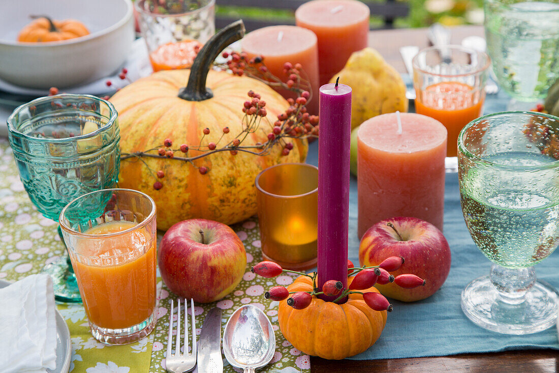 Herbstlich gedeckter Tisch mit Kürbissen, Äpfeln und Kerzen