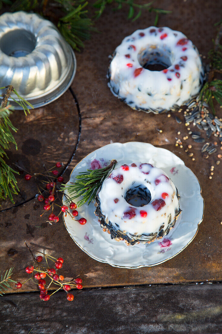 Vogelfutter in Mini-Gugelhupf-Formen mit Beeren und Samen auf rustikaler Unterlage