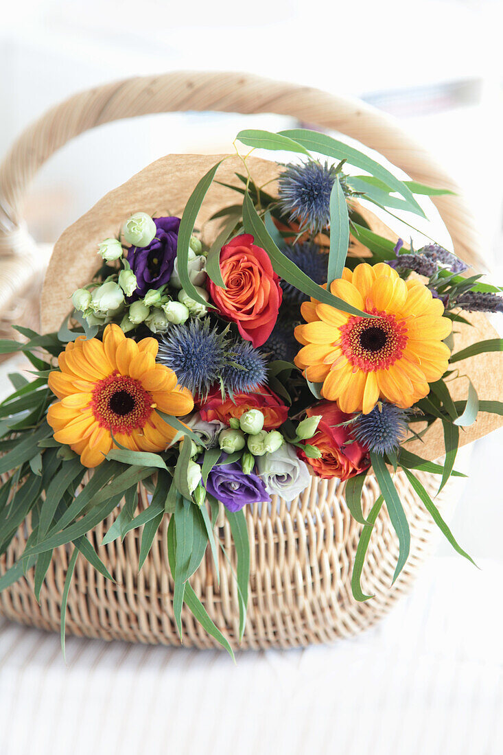 Bouquet of gerberas, roses and thistles in a shopping basket
