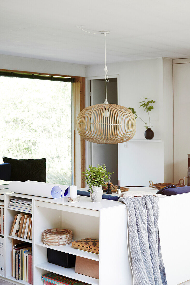 White shelf unit behind the sofa and bamboo lamp