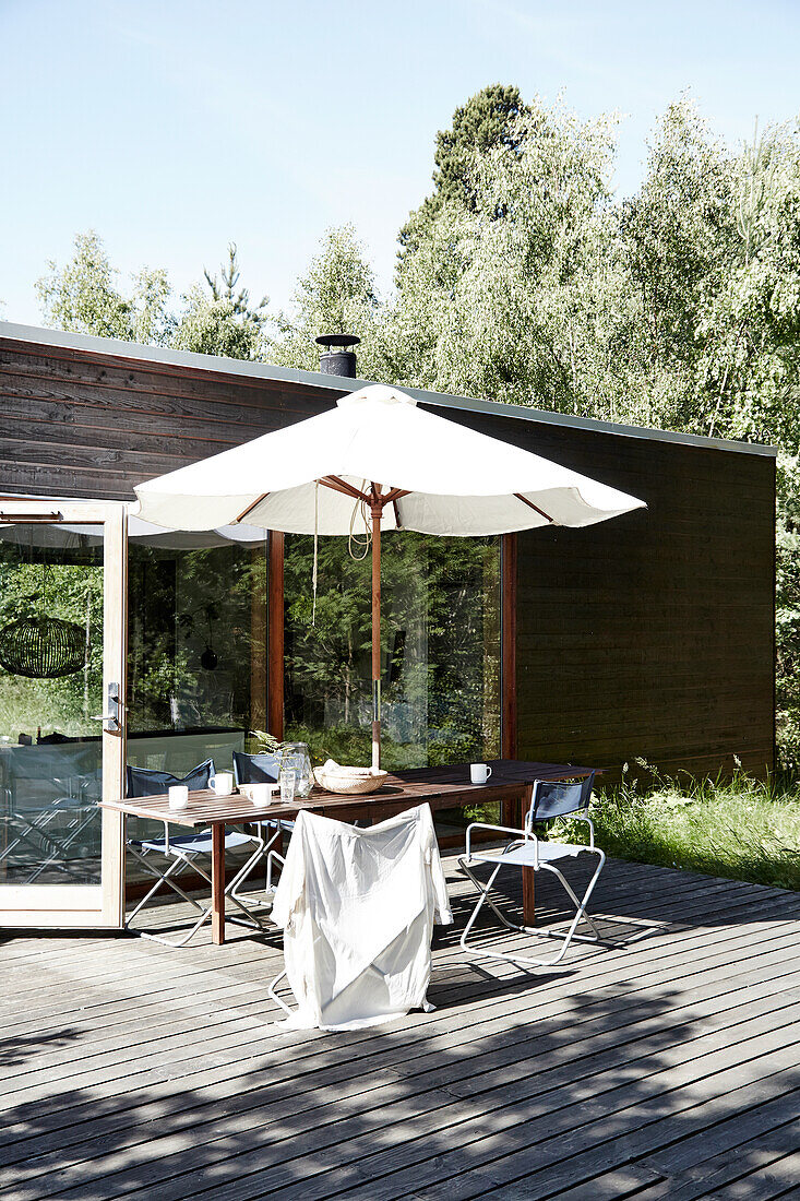 Table with chairs and parasol on wooden terrace