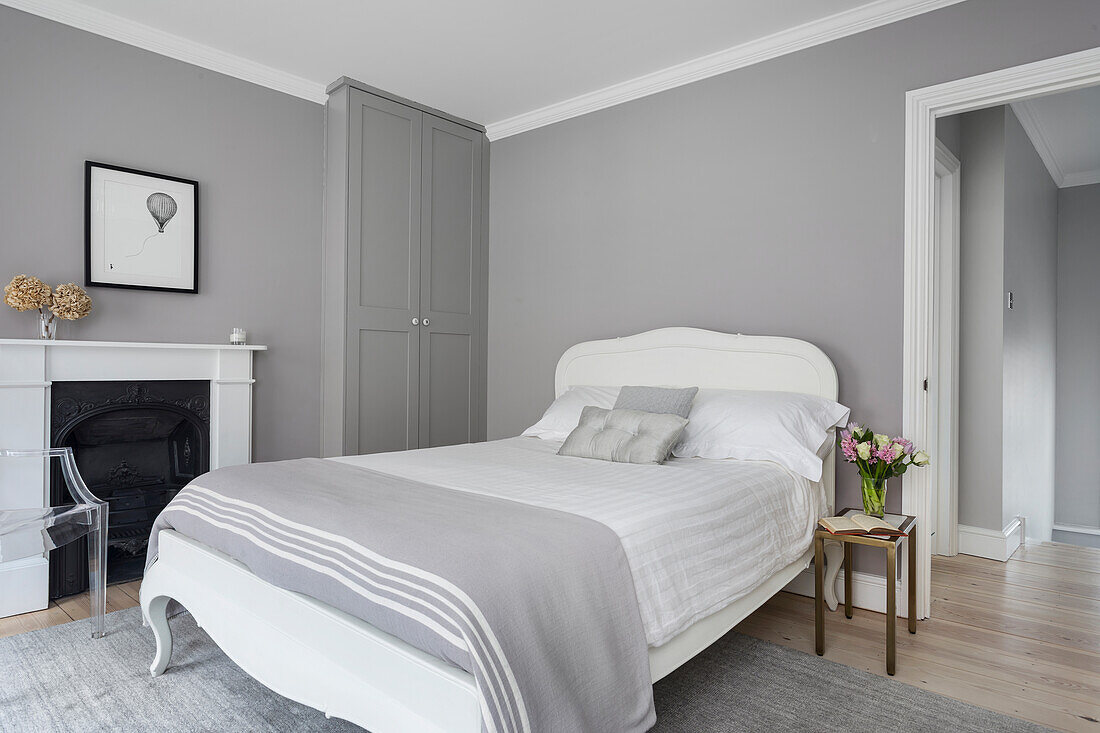 Double bed, built-in wardrobe and fireplace in bedroom with light grey walls