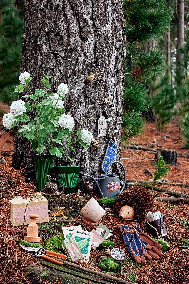 Garden utensils, hedgehog figure and hydrangeas on forest floor - gift idea for gardeners