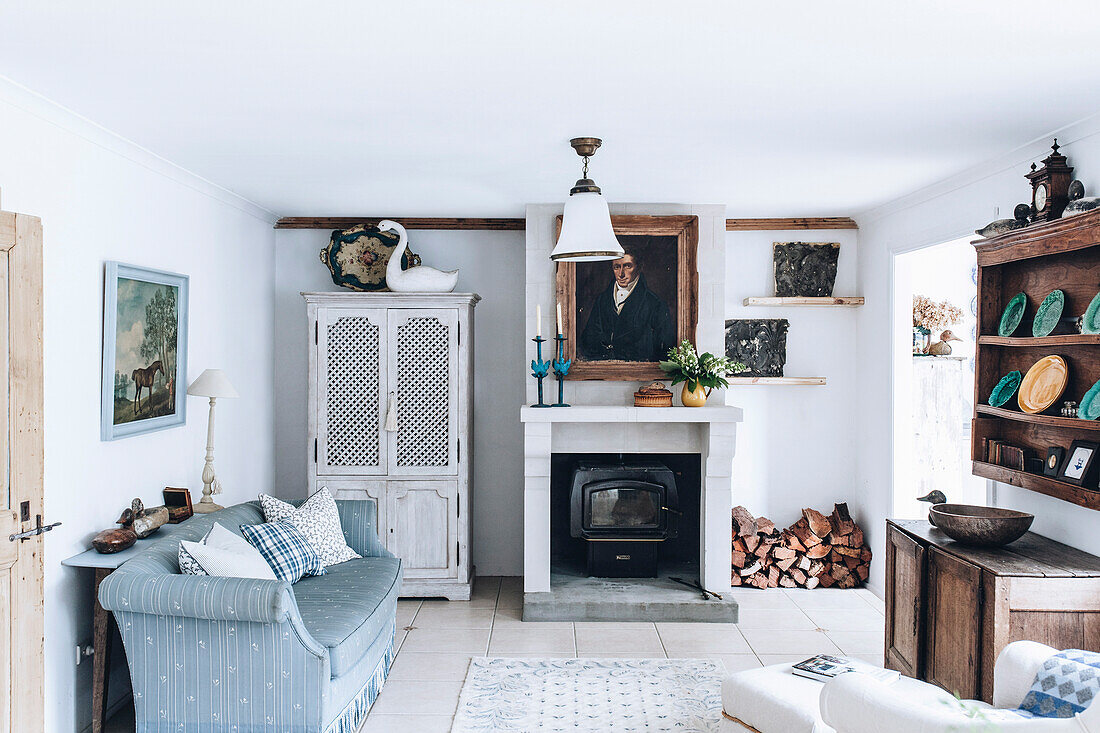 Sofa, Kamin und Anrichte in ländlichem Wohnzimmer mit weißen Wänden