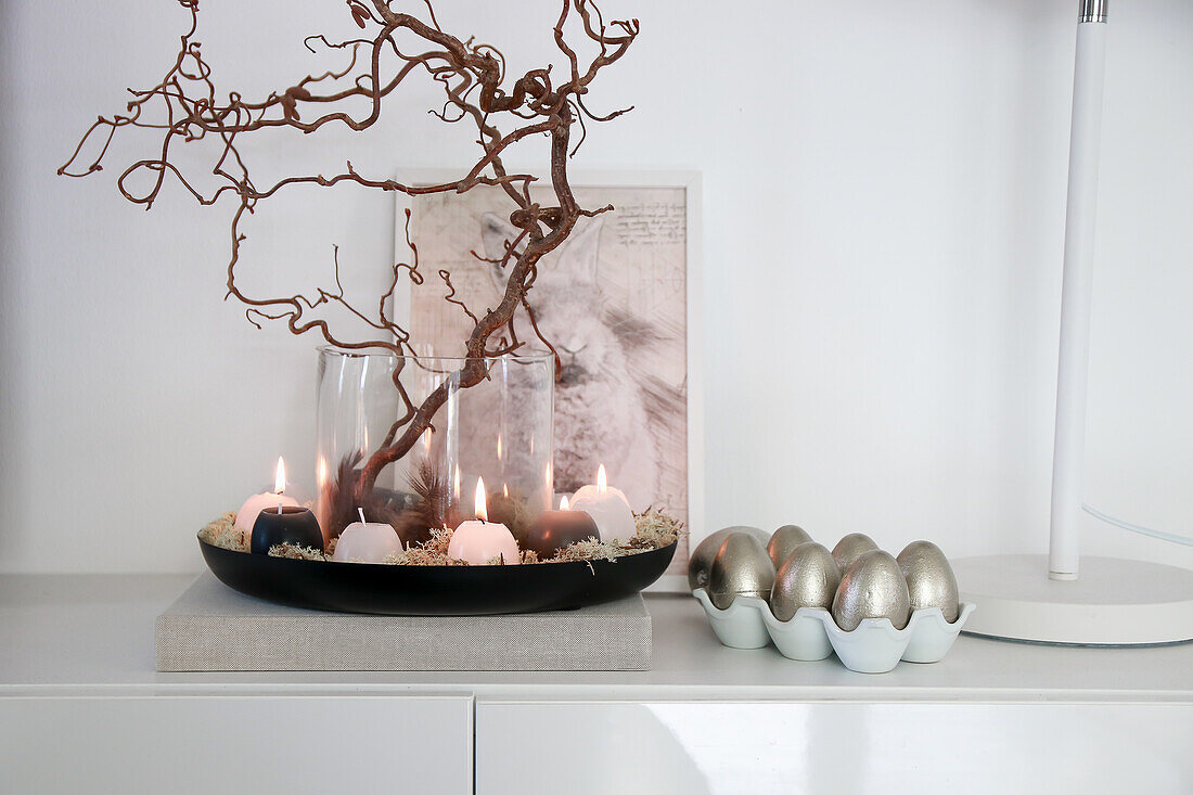 Homemade Easter decoration with candles, branches and silver eggs