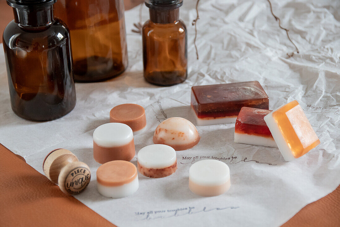 Various handmade soaps on paper, apothecary bottles