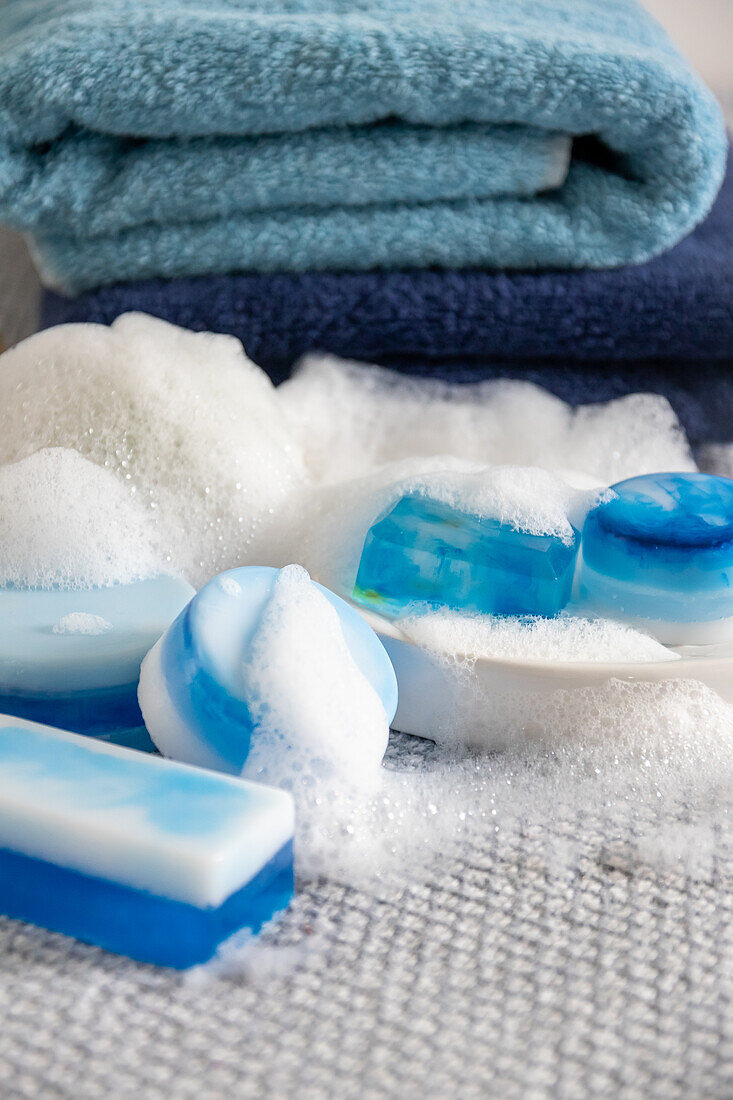 Blue and white soap bars with foam in front of folded towels