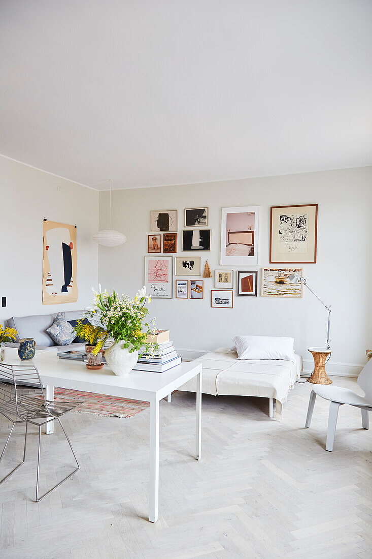 Zwei weiße Tische als Raumteiler zum Wohnzimmer mit Bildergalerie