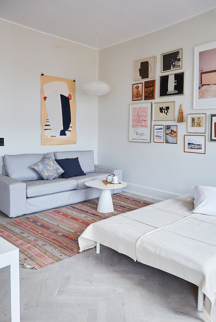 Sofa und Tagesbett vor Bildergalerie im Wohnzimmer in gedeckten Farben
