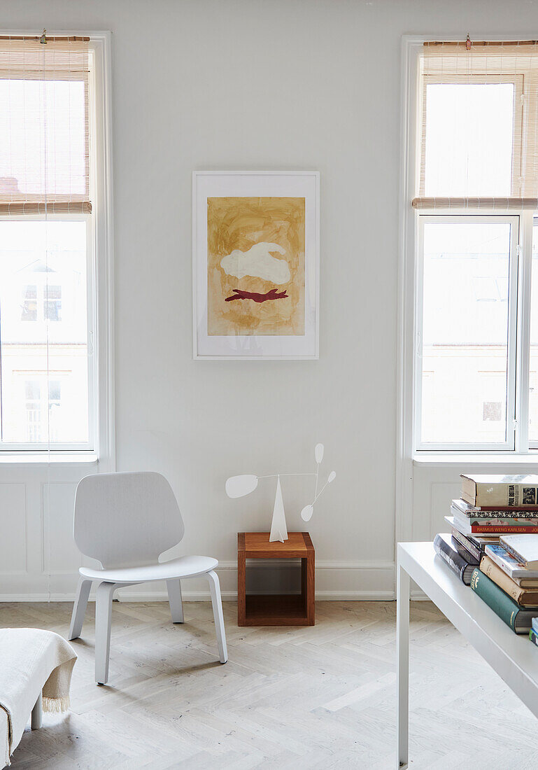 Designerstuhl und Mobile zwischen zwei Altbaufenstern im Wohnzimmer