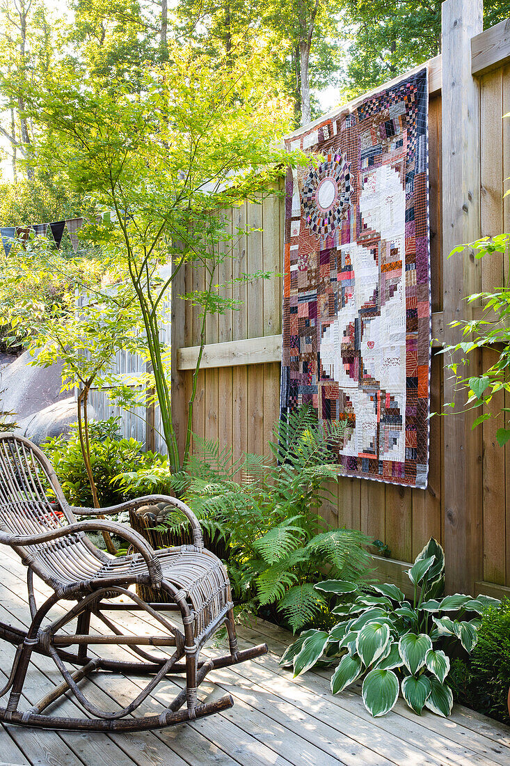 Rocking chair in front of wall hanging on wooden terrace