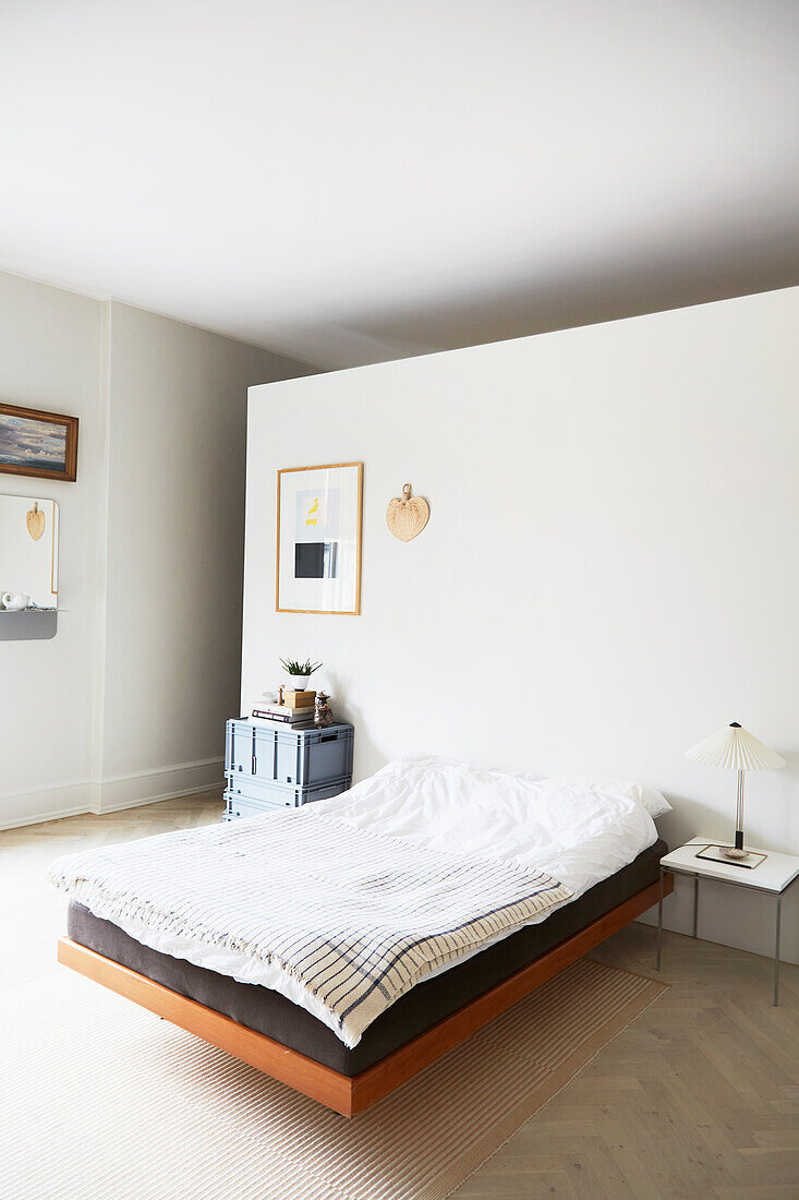 Schwebendes Bett an Raumteilerwand im minimalistischen Schlafzimmer