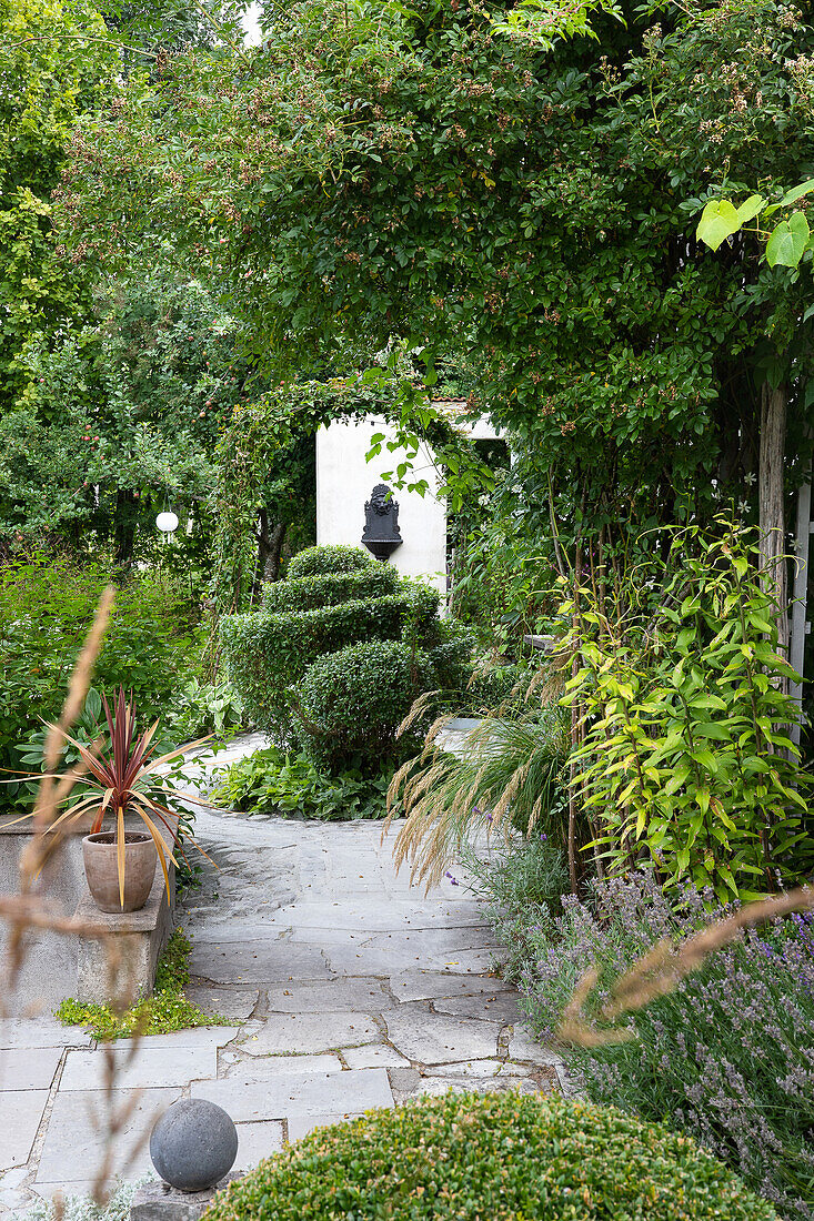 Garden path with a variety of plants and sculpture in the background