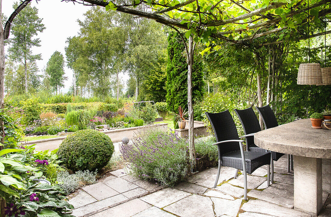 Terrace design with stone table and garden chairs under a pergola