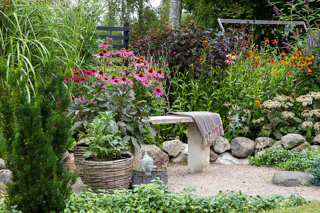 Stone bench with woollen blanket in a colorful perennial garden