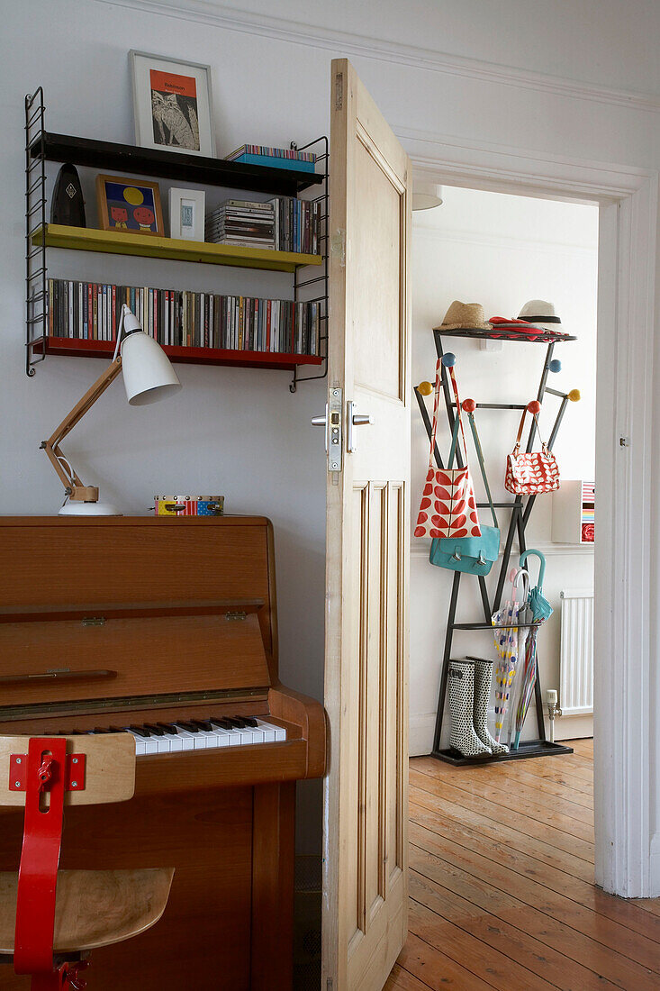 Piano behind open door to hallway with coat stand