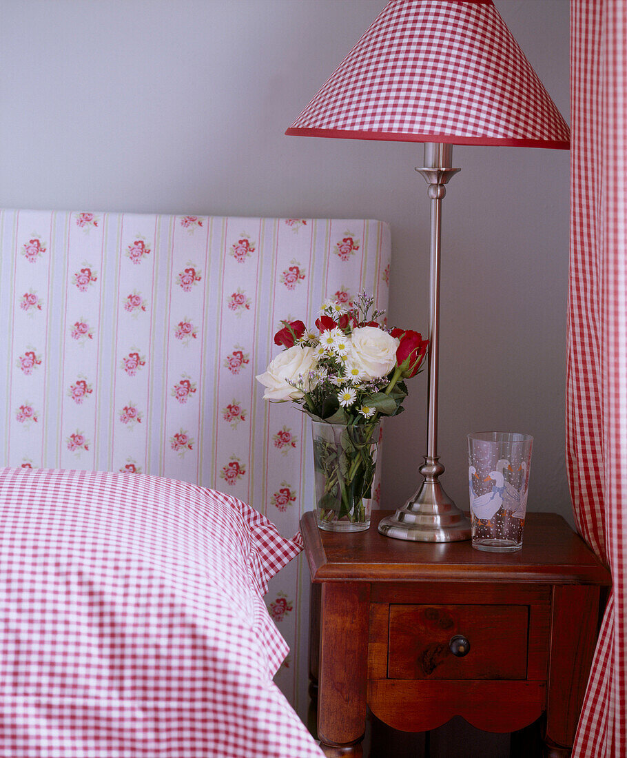Bed with upholstered headboard and lamp with gingham shade