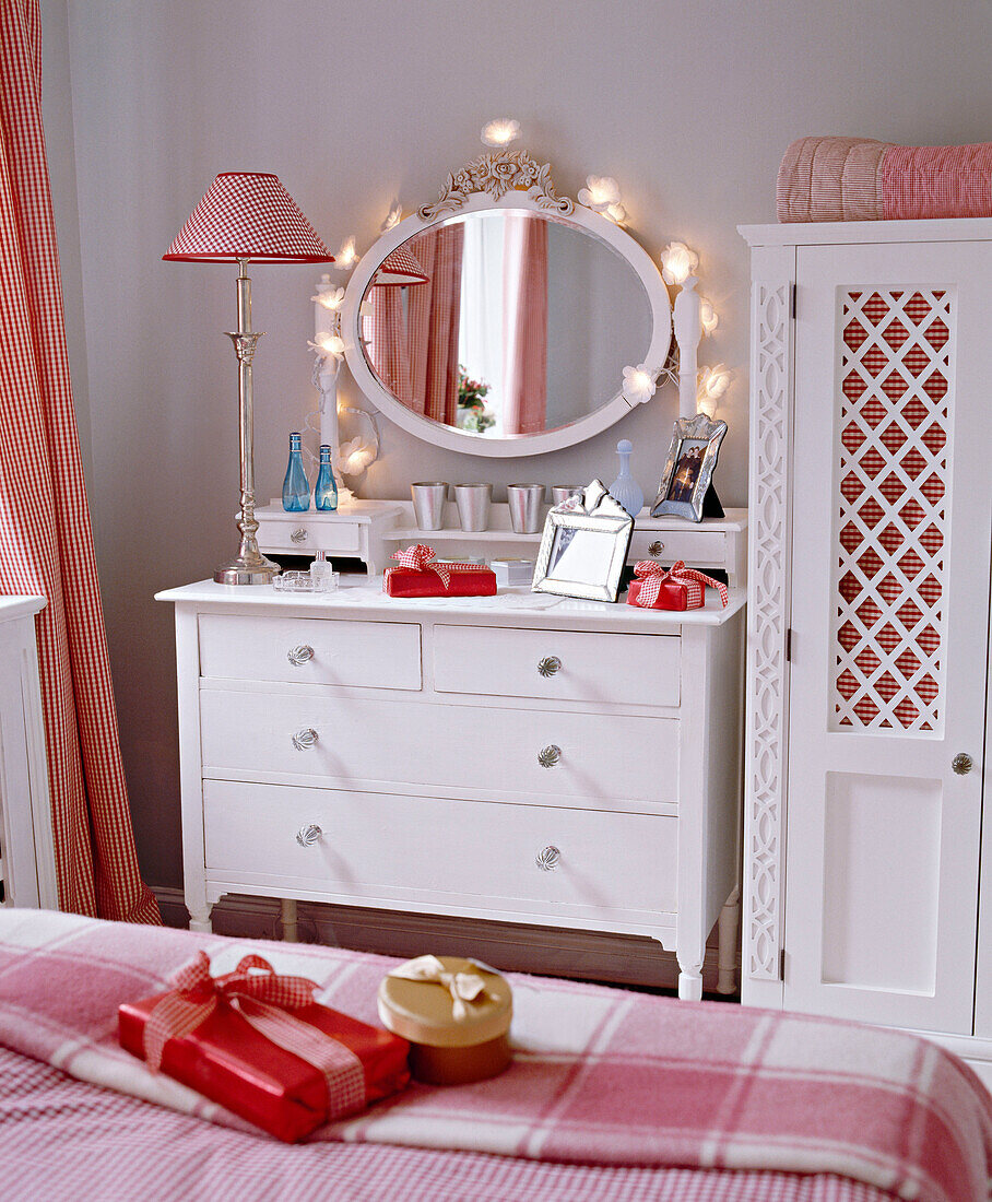 Schlafzimmer mit weiß gestrichener Kommode, Kleiderschrank und karierten Stoffen