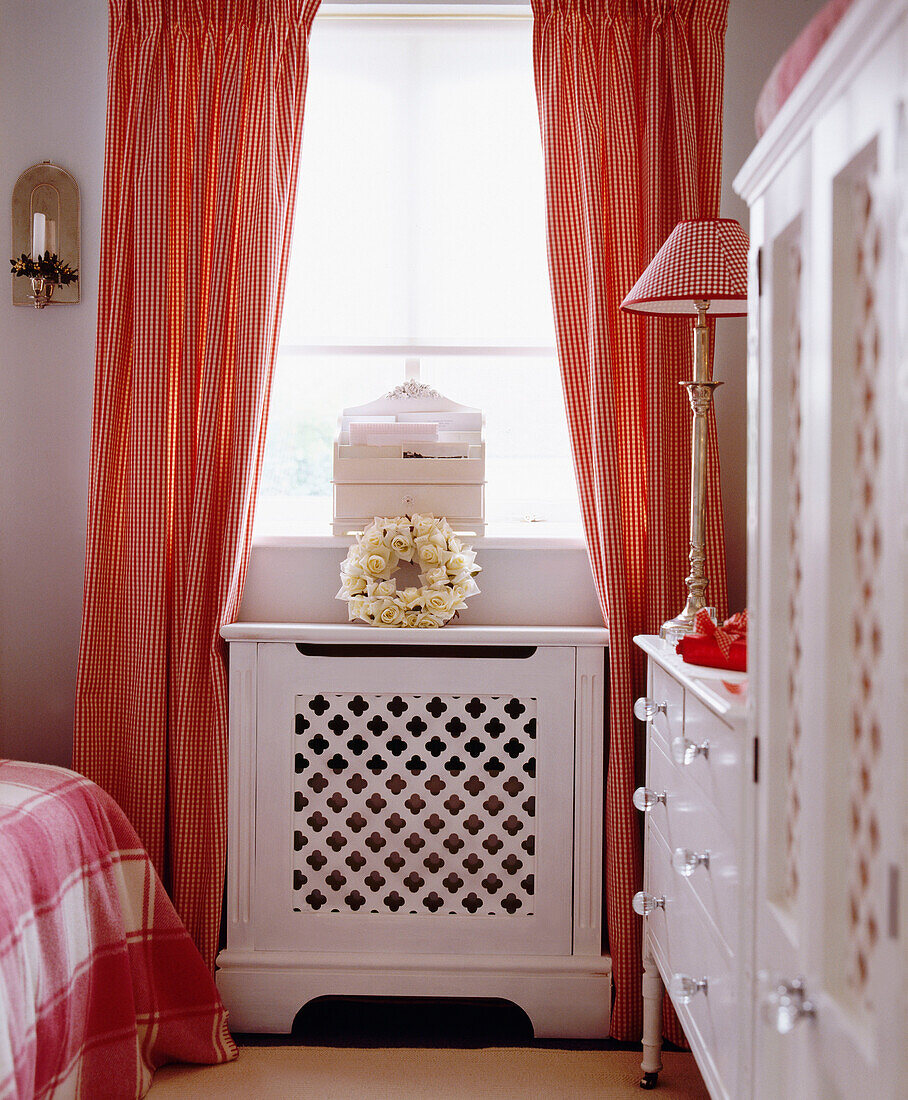 Bedroom with white painted chest of drawers and cabinet and gingham curtains
