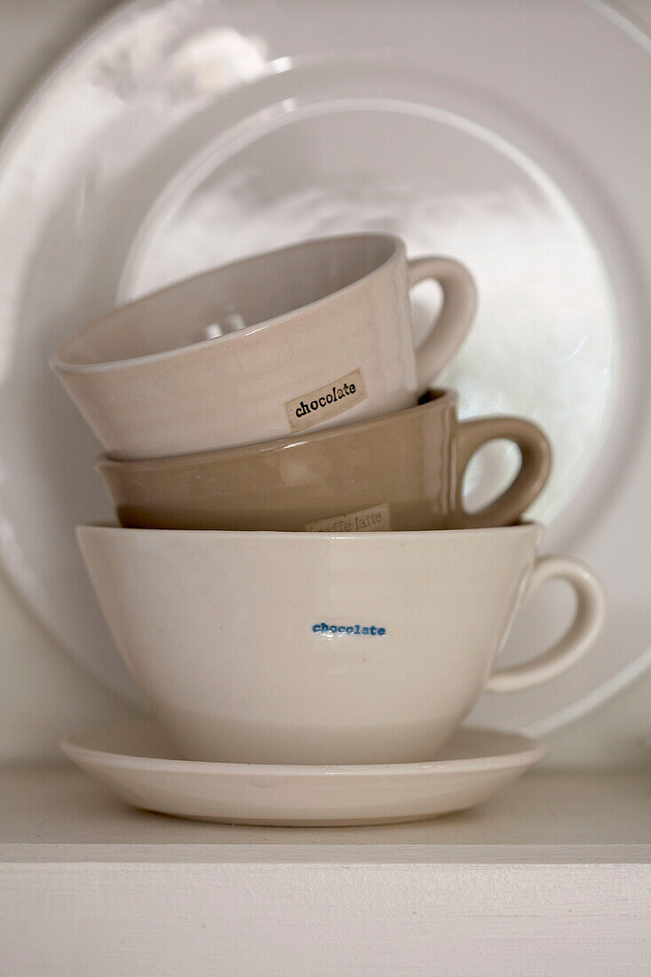 Cups and a plate on a kitchen shelf
