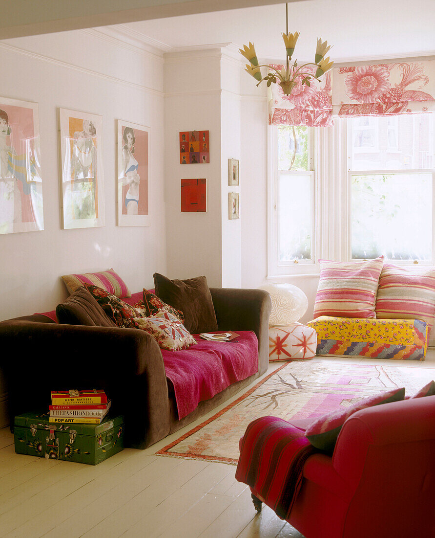 Ein modernes, farbenfrohes Wohnzimmer mit einem mit gerahmten Drucken bedeckten Sofateppich, über dem eine blumenförmige Leuchte hängt
