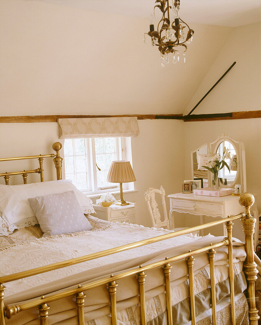 Traditionelles Schlafzimmer mit Vintage-Leuchte, die über Messingbettgestell neben französischem Frisiertisch hängt