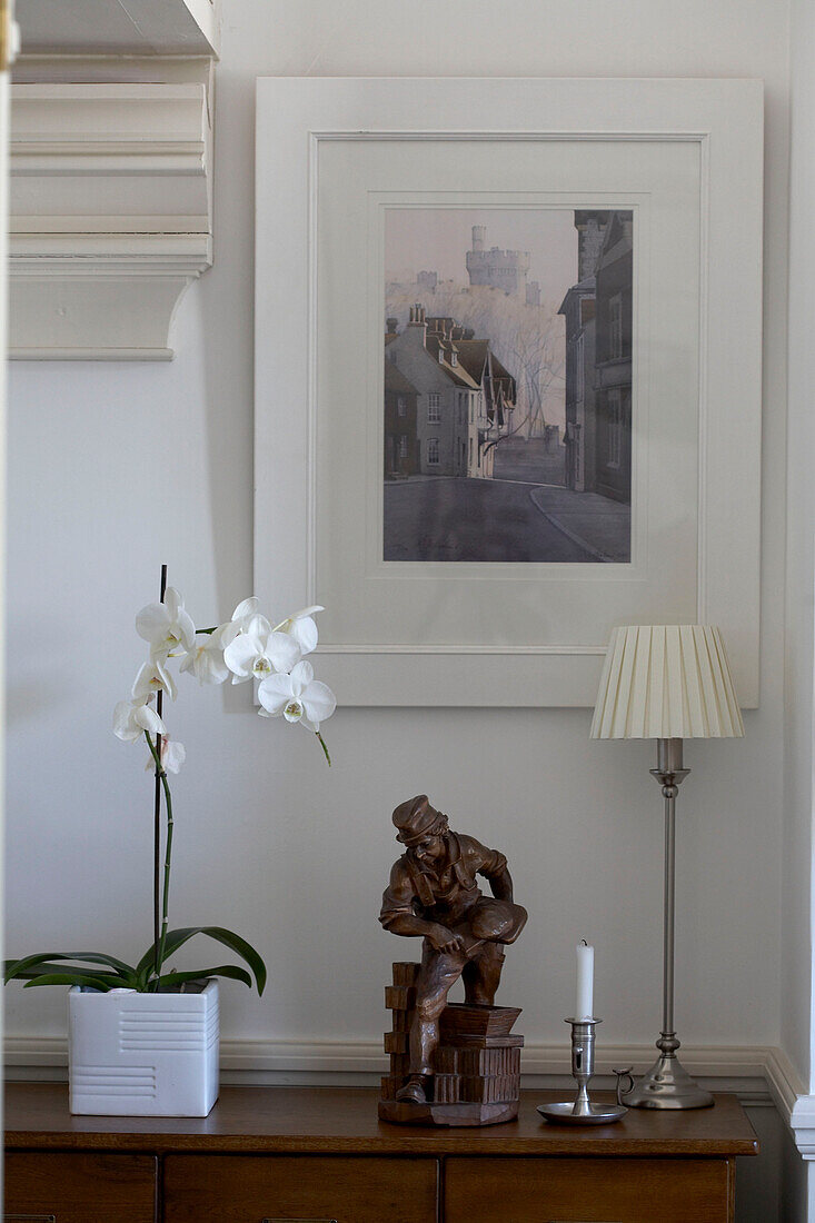 Ornaments and artwork with orchid on wooden sideboard in Arundel new build, Sussex