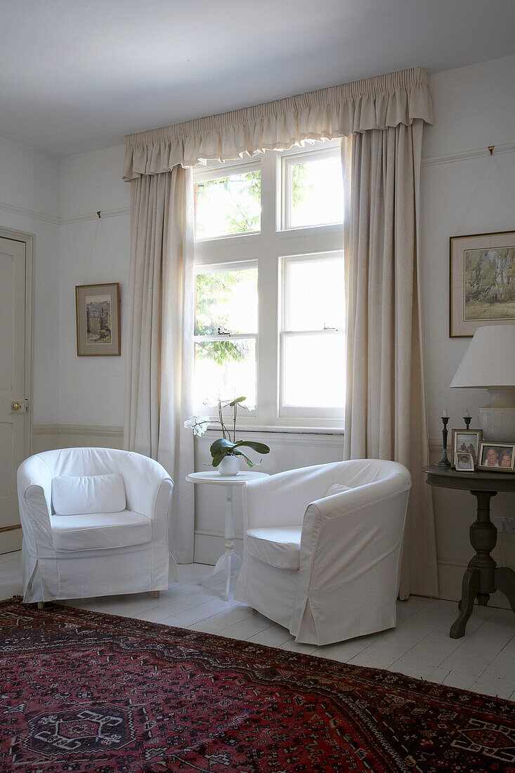 Weiß gepolsterte Sessel am Fenster des Wohnzimmers in Arundel, West Sussex
