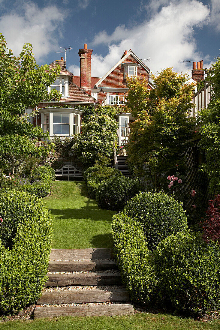 Backsteinhaus von Außen und abfallender Garten mit Rasen in Arundel, West Sussex