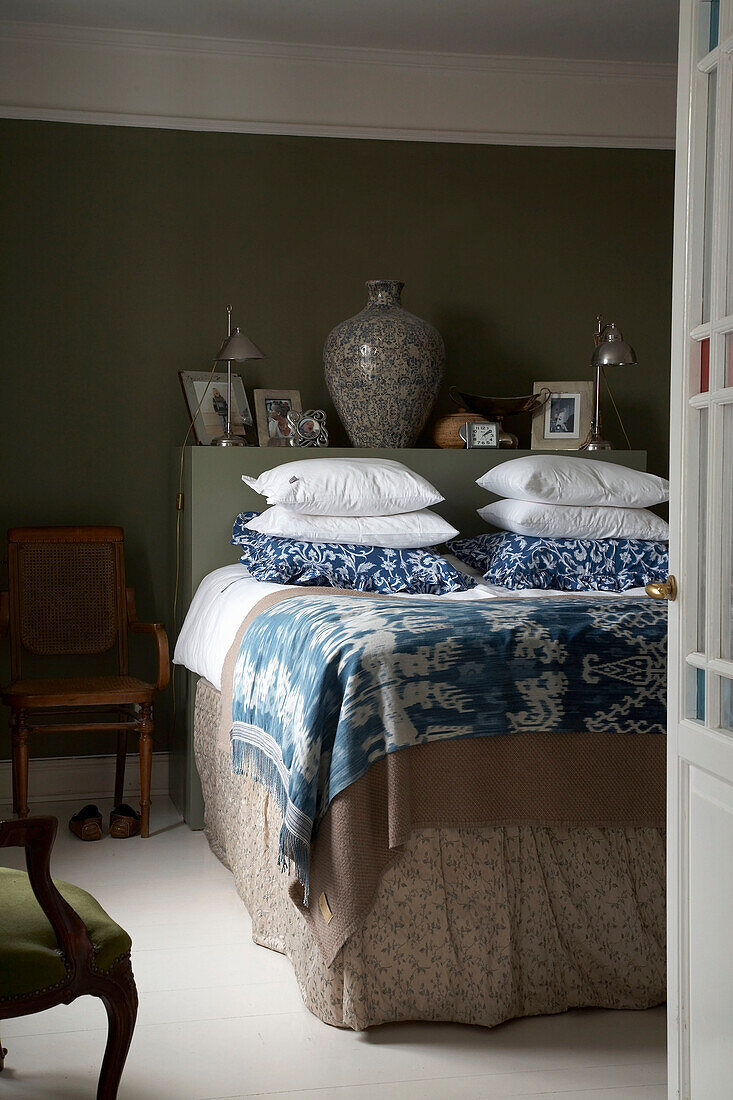 Patterned pillows and blanket on bed with shelf headboard
