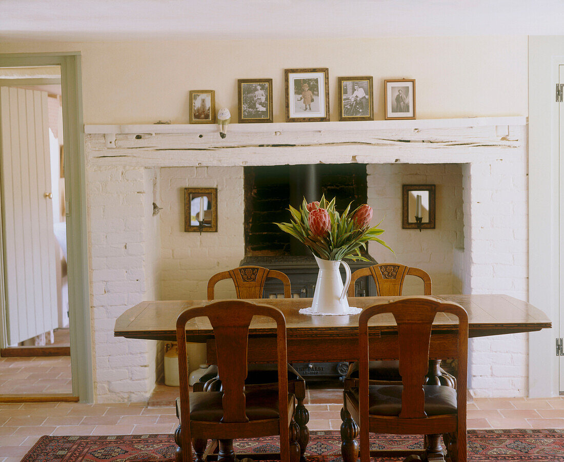 Rustikaler Esstisch aus Holz mit Blumenvase am Kamin in einem Zimmer im Landhausstil