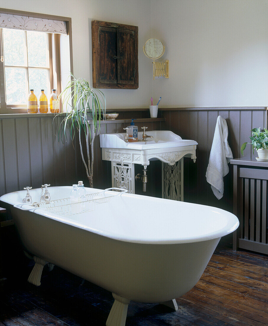 Country style bathroom with a claw foot bathtub ornate sink wood panelling and wood floor