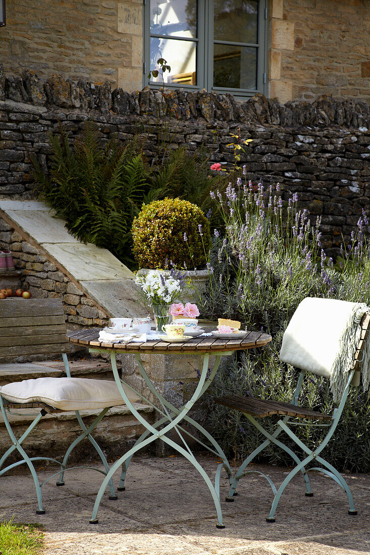 Stuhl und Tisch auf der Terrasse eines Steinhauses in den Cotswolds, England